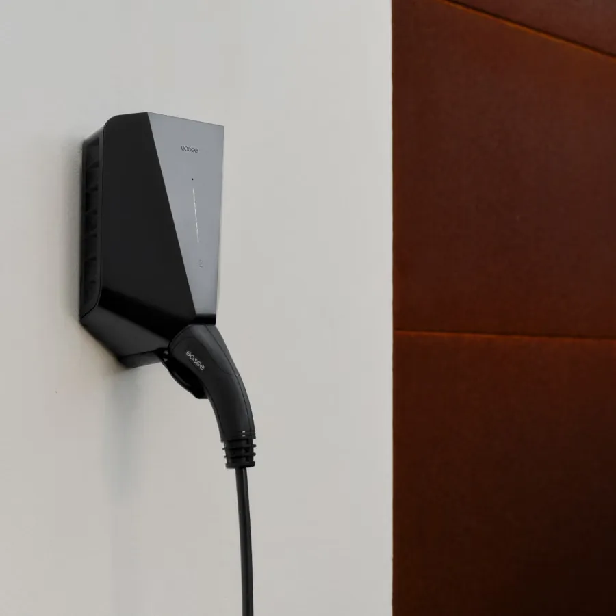 Easee One EV charger mounted on a wall with a charging cable